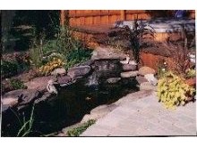 Brick patio, deck, water feature and plantings in Deer Park